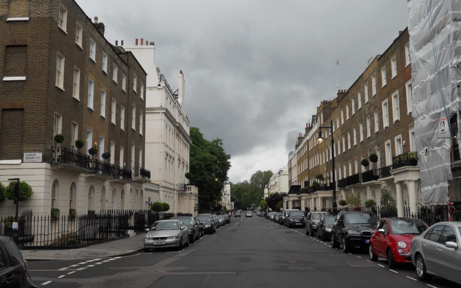 A quiet street of tall Georgian terraced houses in Belgravia, London, with parked cars