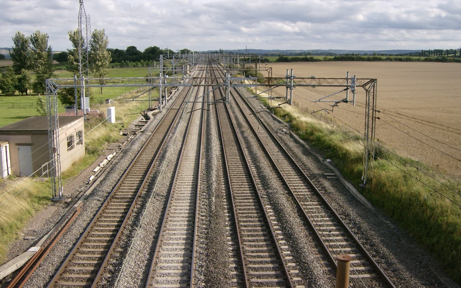 View over a railway line running straight into the distance through flat countryside